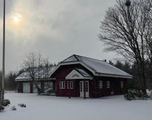 a red barn with snow on the roof at Mosborg Gæstehus in Ulfborg
