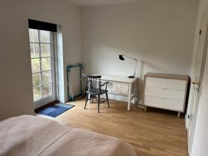 a bedroom with a desk and a chair next to a window at Mosborg Gæstehus in Ulfborg