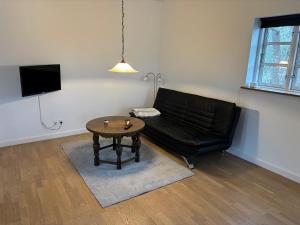 a living room with a black leather couch and a table at Mosborg Gæstehus in Ulfborg
