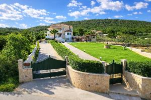 a house with a gate in front of a yard at Bella Villa with Private Pool & Sea View Ideal for Groups in Vaia