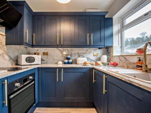 a kitchen with blue cabinets and a sink and a window at 2 Bed in Swansea oc-90367 in Oxwich +12 photos
