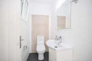 a white bathroom with a toilet and a sink at Villa Leo in Barbati +8 photos