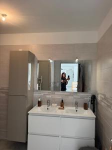 a woman taking a picture of a bathroom with a sink at Hearttoart in Martigues