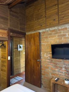 a room with a television and a brick wall at Cabañas Valle del Cocora La Truchera in Salento