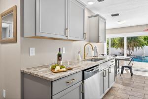 a kitchen with white cabinets and a sink and a table at Heated PoolFoosball,Pac Man Arcade, walk to beach in Clearwater Beach
