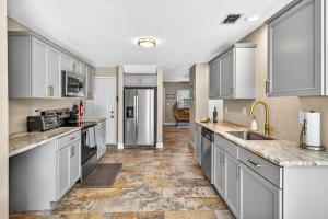 a large kitchen with white cabinets and a tile floor at Heated PoolFoosball,Pac Man Arcade, walk to beach in Clearwater Beach +35 photos