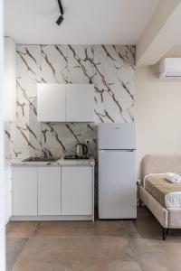 a kitchen with white cabinets and a marble wall at Zoe's Villa by PS in Durrës