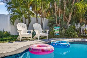 two chairs and a swimming pool with two inflatables at Steps to beachTiki BarHeated Poolfun! in Clearwater Beach