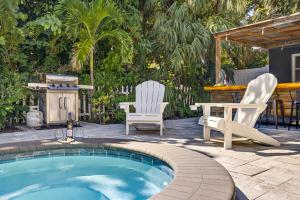 a swimming pool with two chairs and a table at Steps to beachTiki BarHeated Poolfun! in Clearwater Beach