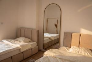 two beds in a room with a mirror at Inviti Apartments in Gjakove