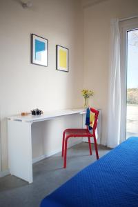 a white desk with a red chair in a bedroom at Petrikore - Rosso in Scoglitti +10 photos