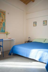 a bedroom with a blue bed and a desk at Petrikore - Rosso in Scoglitti