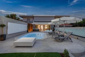a pool with chairs and umbrellas on a patio at AZURE Seaside Residence in Kokkini Khanion