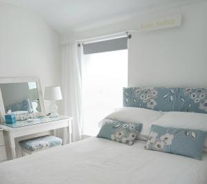 a white bedroom with a bed with a mirror and a window at Uwch Menai in Y Felinheli