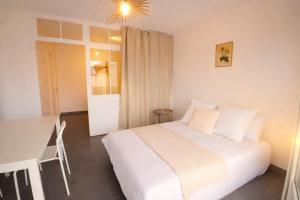 a bedroom with a white bed and a table at L'Albatros - Appartement de charme à Digoin in Digoin