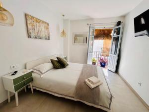 a white bedroom with a bed and a window at Fabulous 2 bed-townhouse with large rooftop! in Estepona