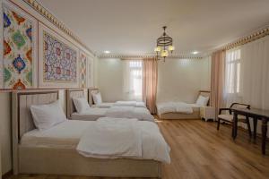 a bedroom with three beds and a desk at SHakhina premium hotel in old city in Bukhara