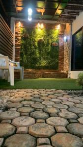 a stone patio with a green wall and a bench at Digong Guest House Mulogan in Molugan