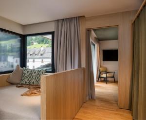 a bedroom with a bed and a large window at Hotel Mühlenerhof in Campo Tures