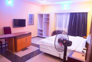 a room with a bed with a desk and a fan at Boripe Hotel And Suites, Oluponna, Osun State in Olupona