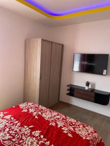 a bedroom with a red bed and a flat screen tv at Chambres pour 1 ou 2 personnes in Prayssac