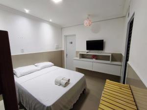 a bedroom with a bed and a tv on the wall at Essenza Suites Natal in Natal