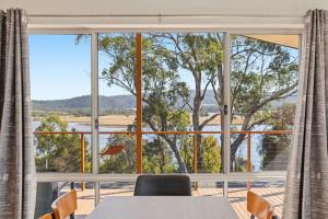a room with a large window with a table and chairs at Tranquil Escape by the Water in Triabunna