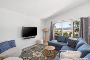 a living room with a blue couch and a tv at Tranquil Escape by the Water in Triabunna