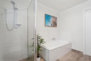 a white bathroom with a shower and a bath tub at Tranquil Escape by the Water in Triabunna +27 photos