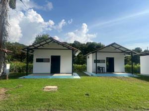 a small white house with two doors in a yard at Shaddai Villeta Centro Ecoturistico in Villeta