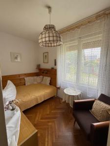 a bedroom with a bed and a couch and a chandelier at Balatonlak in Ábrahámhegy +5 photos