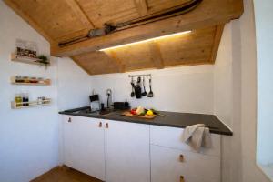 a kitchen with white cabinets and wooden ceilings at Modernes Apartment mit Alpenblick, Balkon & Parkplatz nahe Thun und Interlaken in Thun +5 photos