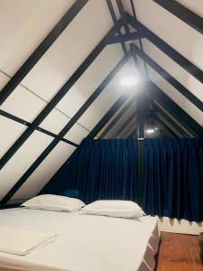 a white bed in a room with a blue curtain at Rainforest Mountain Escape - Lankagama in Deniyaya