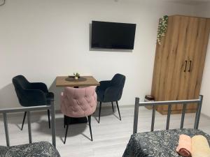 a room with a table and chairs and a television at King Rooms in Novi Kneževac