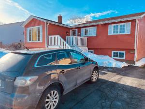 a car parked in front of a red house at The Comfort Pearl in Topsail