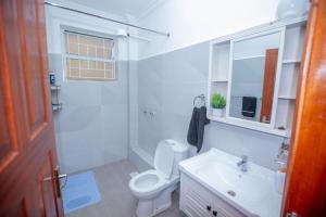 a white bathroom with a toilet and a sink at The Prestige Hub Residences in Eldoret
