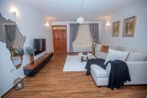 a living room with a white couch and a tv at The Prestige Hub Residences in Eldoret