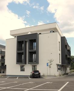 a white building with a car parked in a parking lot at Elegance Apartments in Baile Felix