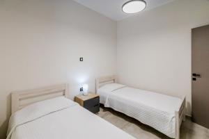 two beds in a room with white walls at Angie's Central Apartment in Pappadhiánika