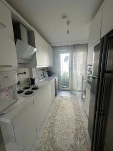 a kitchen with white cabinets and a rug on the floor at Konyaaltı gürsu denize sıfır sahilde full eşyalı lüks daire in Antalya +15 photos
