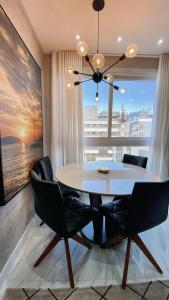 a dining room with a table and chairs and a large window at Loft sua morada in Capão da Canoa