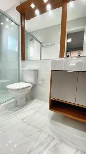 a bathroom with a toilet and a sink and a mirror at Loft sua morada in Capão da Canoa