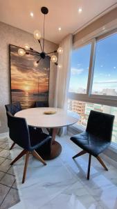 a dining room with a white table and chairs at Loft sua morada in Capão da Canoa