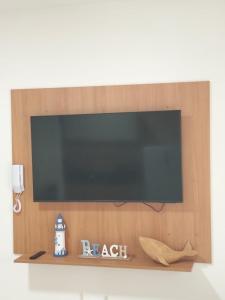 a flat screen tv on a wall with a shelf at Casa da Dinda 103 in Rio das Ostras
