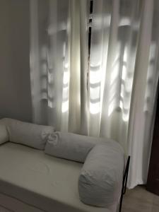 a bed with two pillows in front of a window at Casa da Dinda 103 in Rio das Ostras +1 photo
