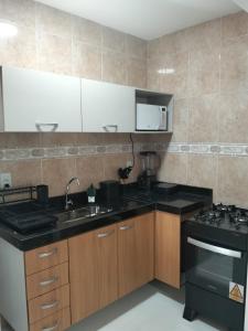 a kitchen with a sink and a stove at Casa da Dinda 103 in Rio das Ostras