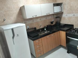 a kitchen with a white refrigerator and a sink at Casa da Dinda 103 in Rio das Ostras