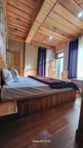 a large bed in a room with wooden ceilings at tirthan horizon homestay in Banjār
