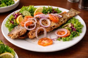 a plate of food with fish and vegetables on a table at Great Victoria Palace in Ratnapura