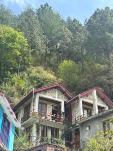 a stone house with a balcony on top of it at tirthan horizon homestay in Banjār